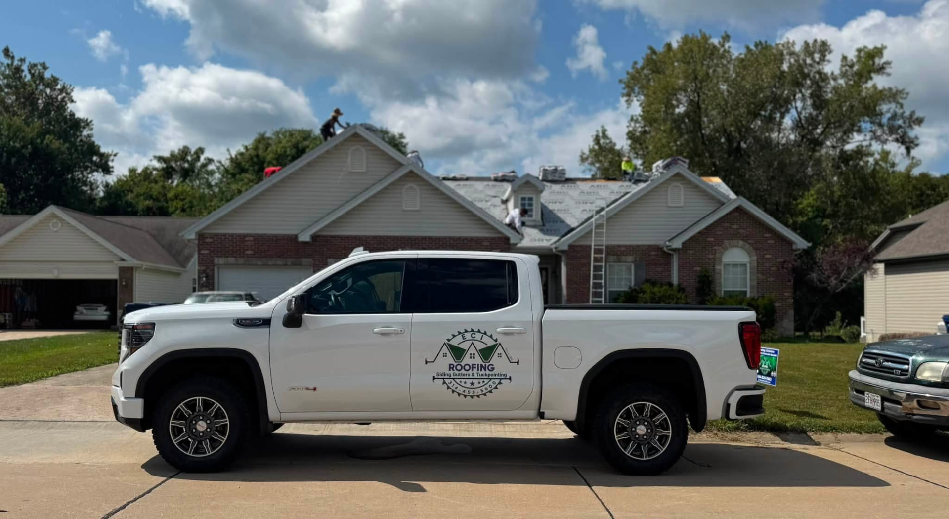 ECI truck at a brick home while the crew works the roof