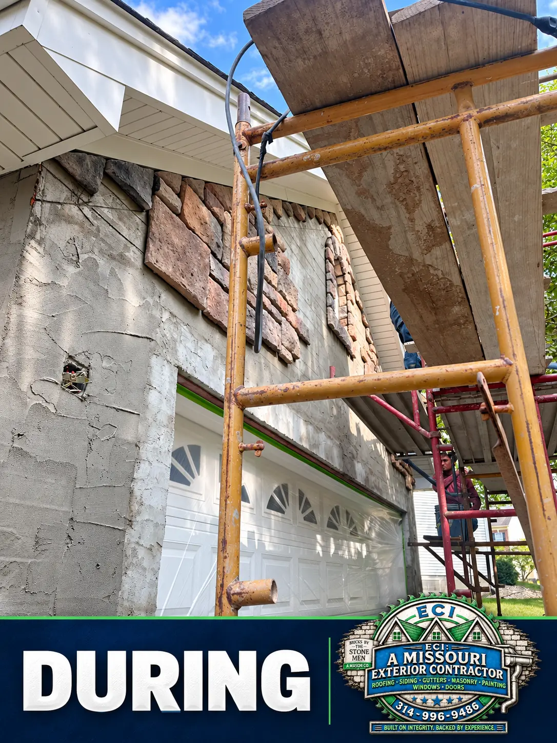 Stone veneer installation underway above the garage doors
